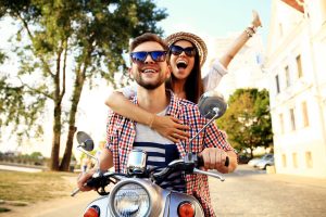 a man and a woman riding on the back of a scooter.